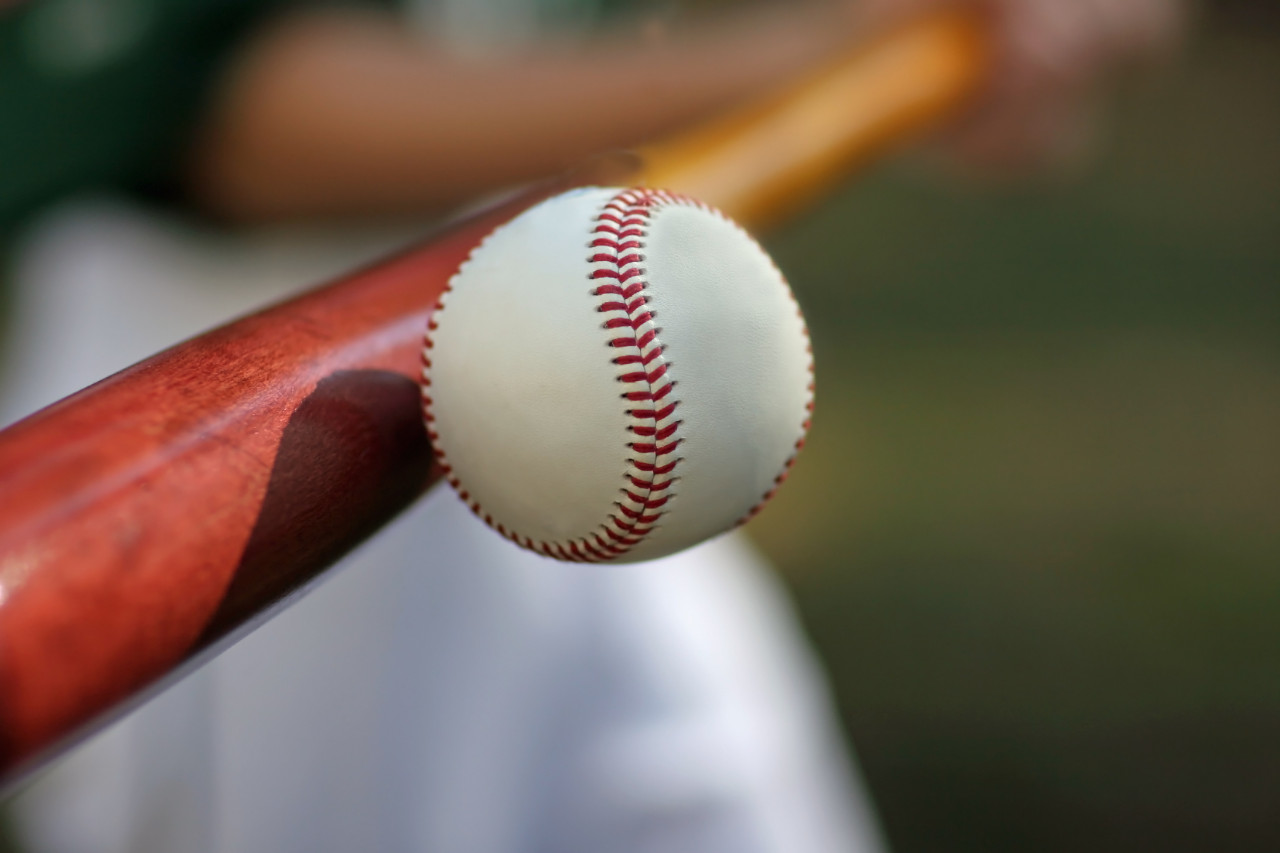 Close-up of a baseball player hitting a ball.